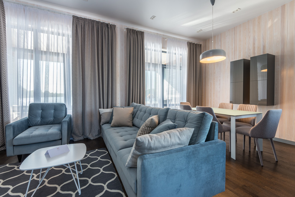 furnished living room with elegant blue couch and big windows